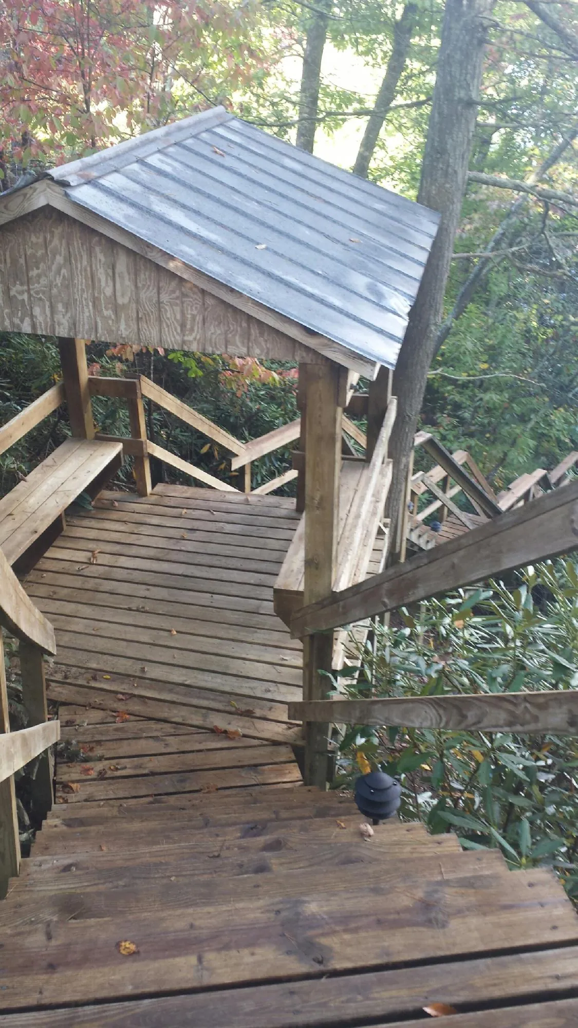 Metal roofed shelter over wooden steps on a wooded walkway — Skylight Repair & Installation work by our crew in Clarksburg